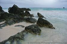 Black rocks battered by waves at Horseshoe Bay Beach.jpg